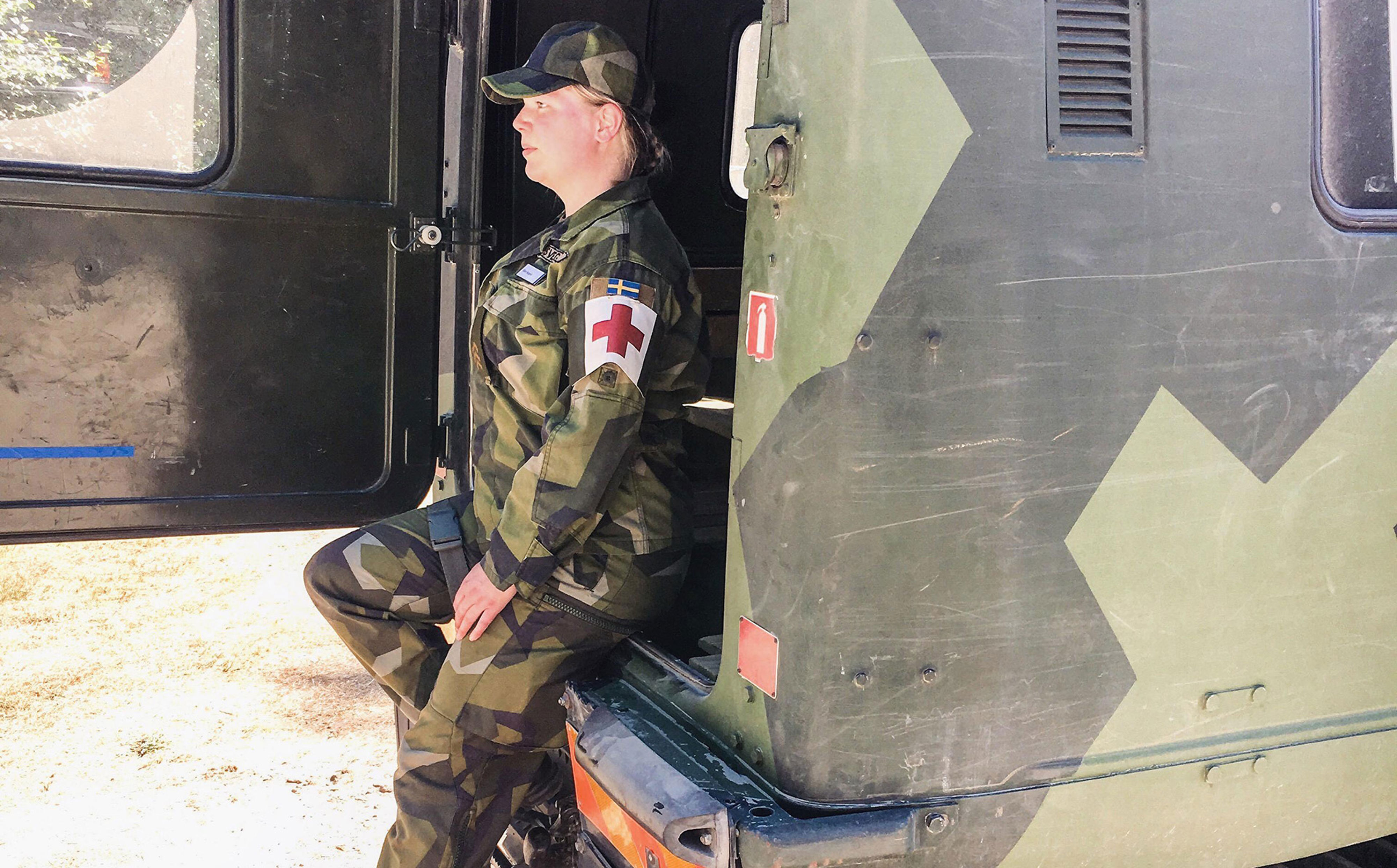 En kvinnlig militär sjukvårdare bredvid en lastbil.