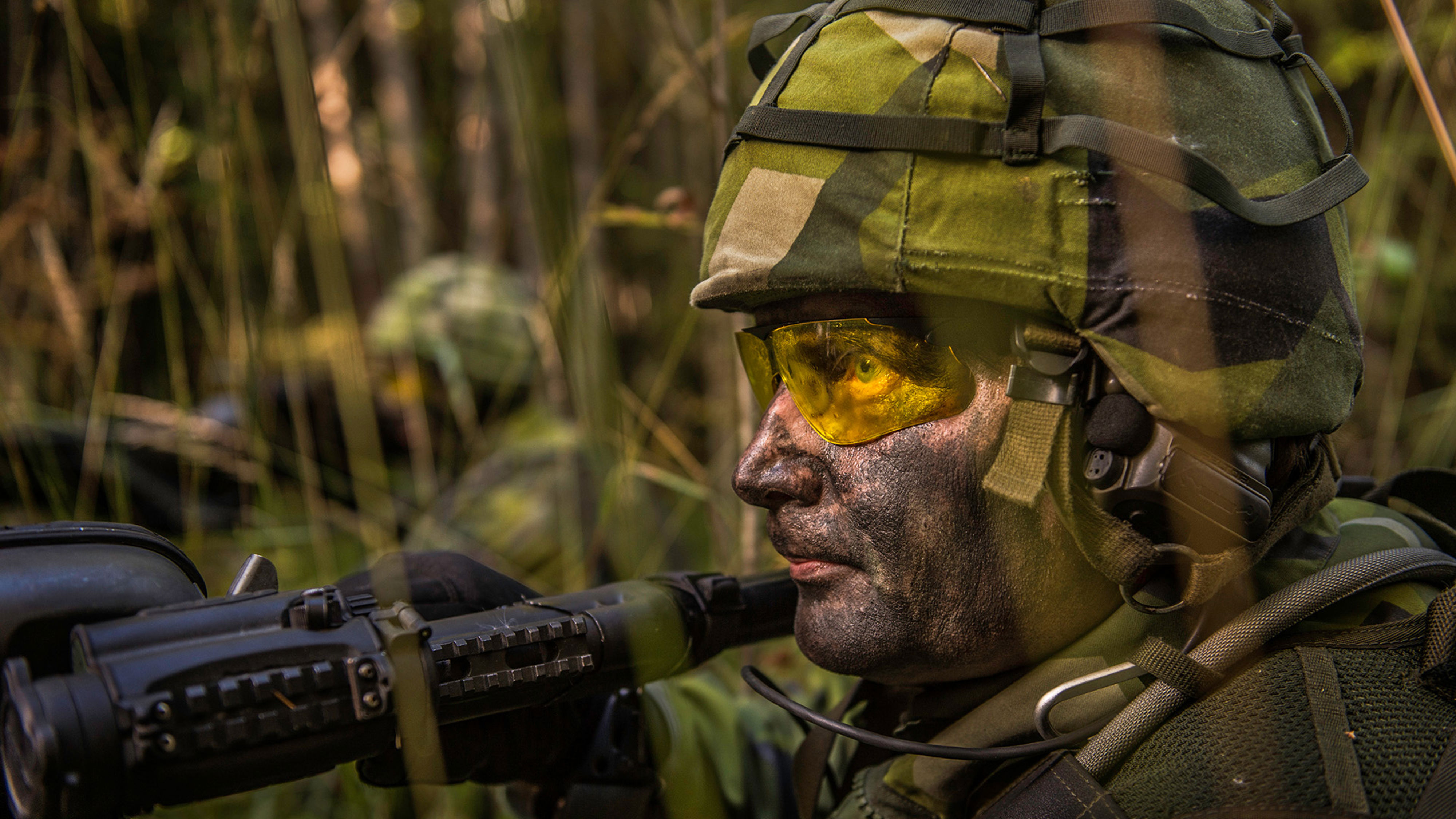 Maskerad soldat i fält med vapen.