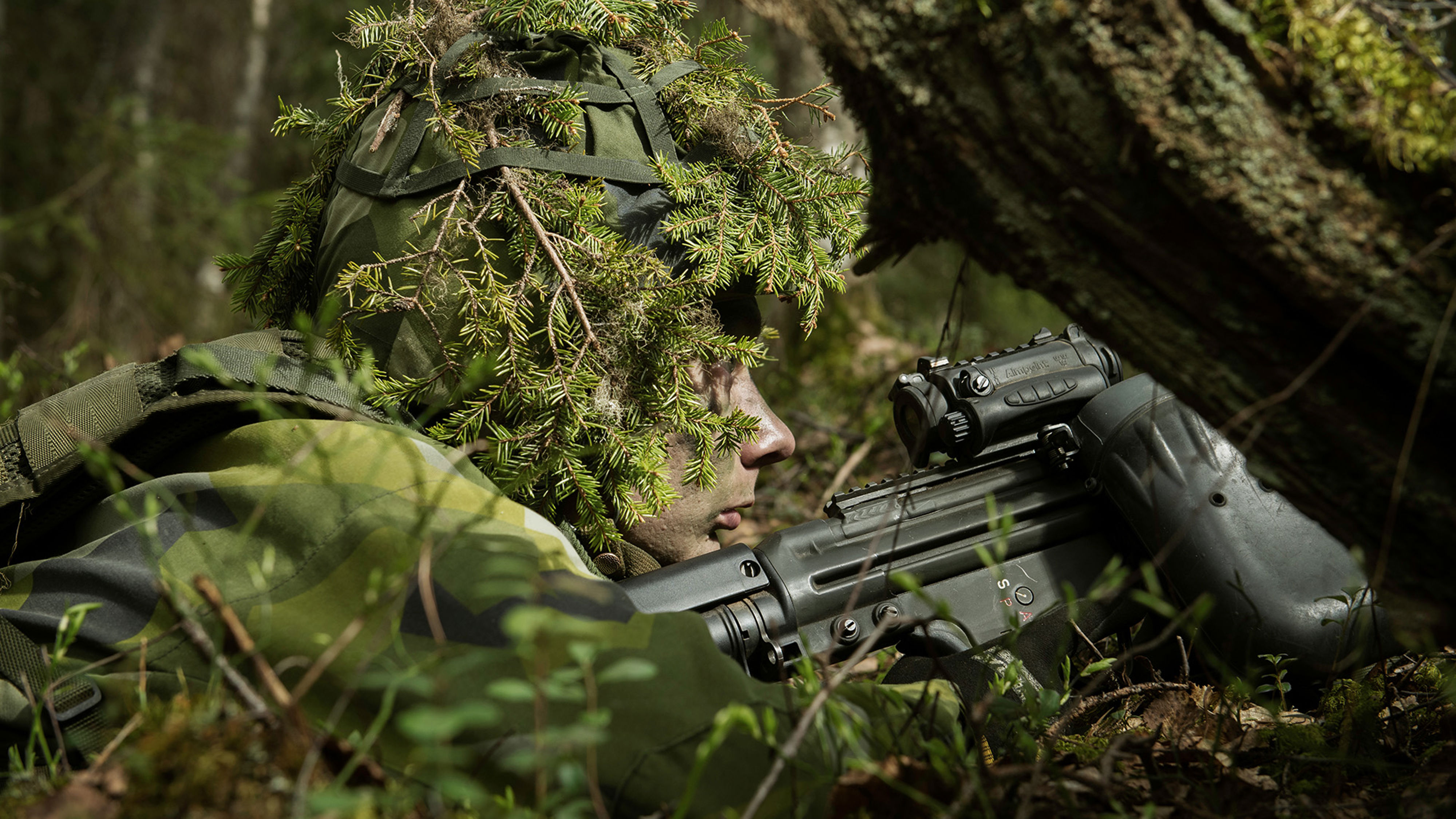 Närbild på soldat i skogen med vapen.