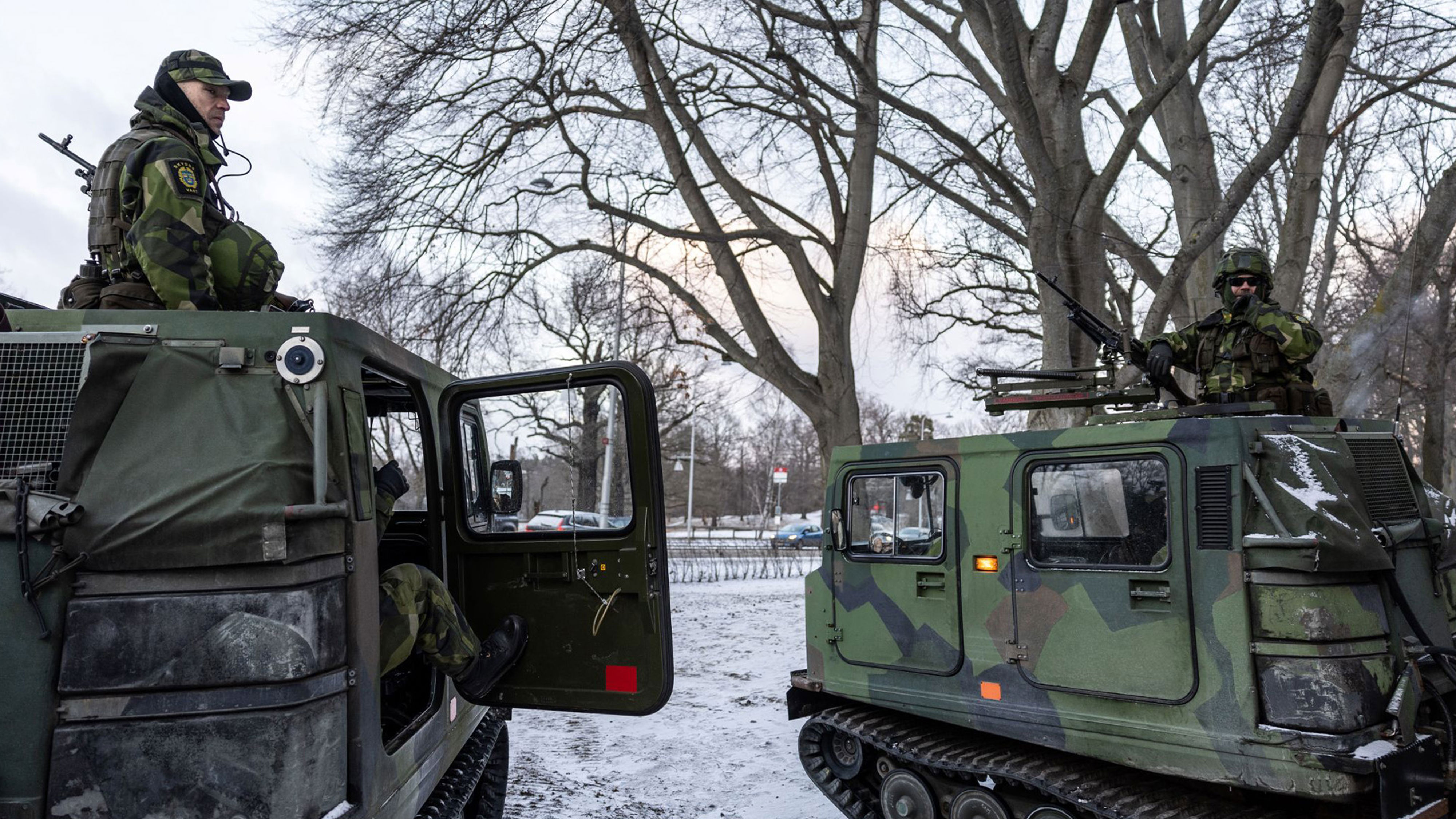 Två soldater sitter i varsin bandvagn i vintermiljö.