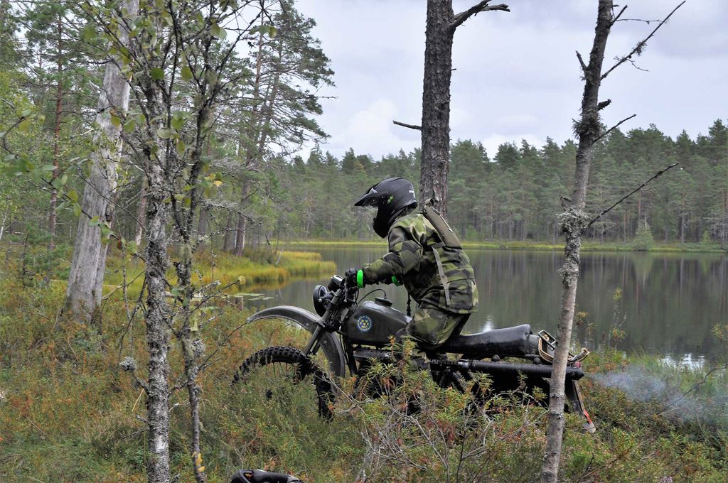 Militär på en motorcykel i skogen