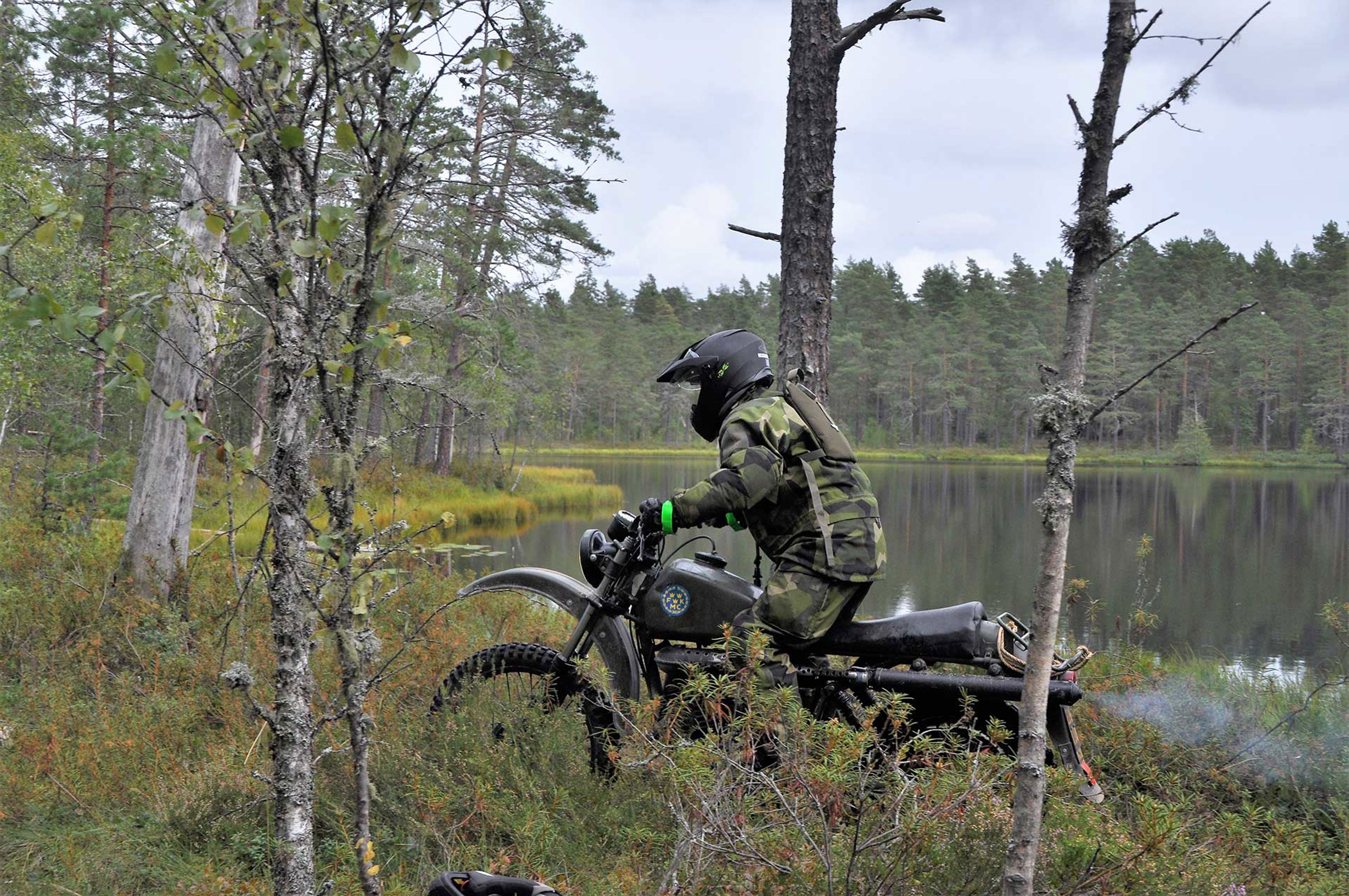 Militär på en motorcykel i skogen