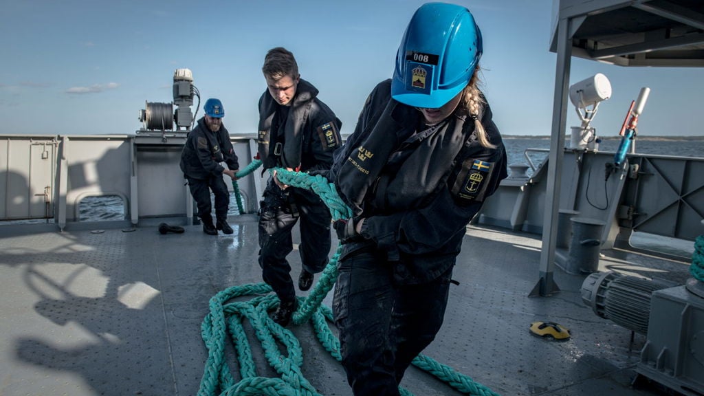Sjömän drar upp bogsertrossen på däck.