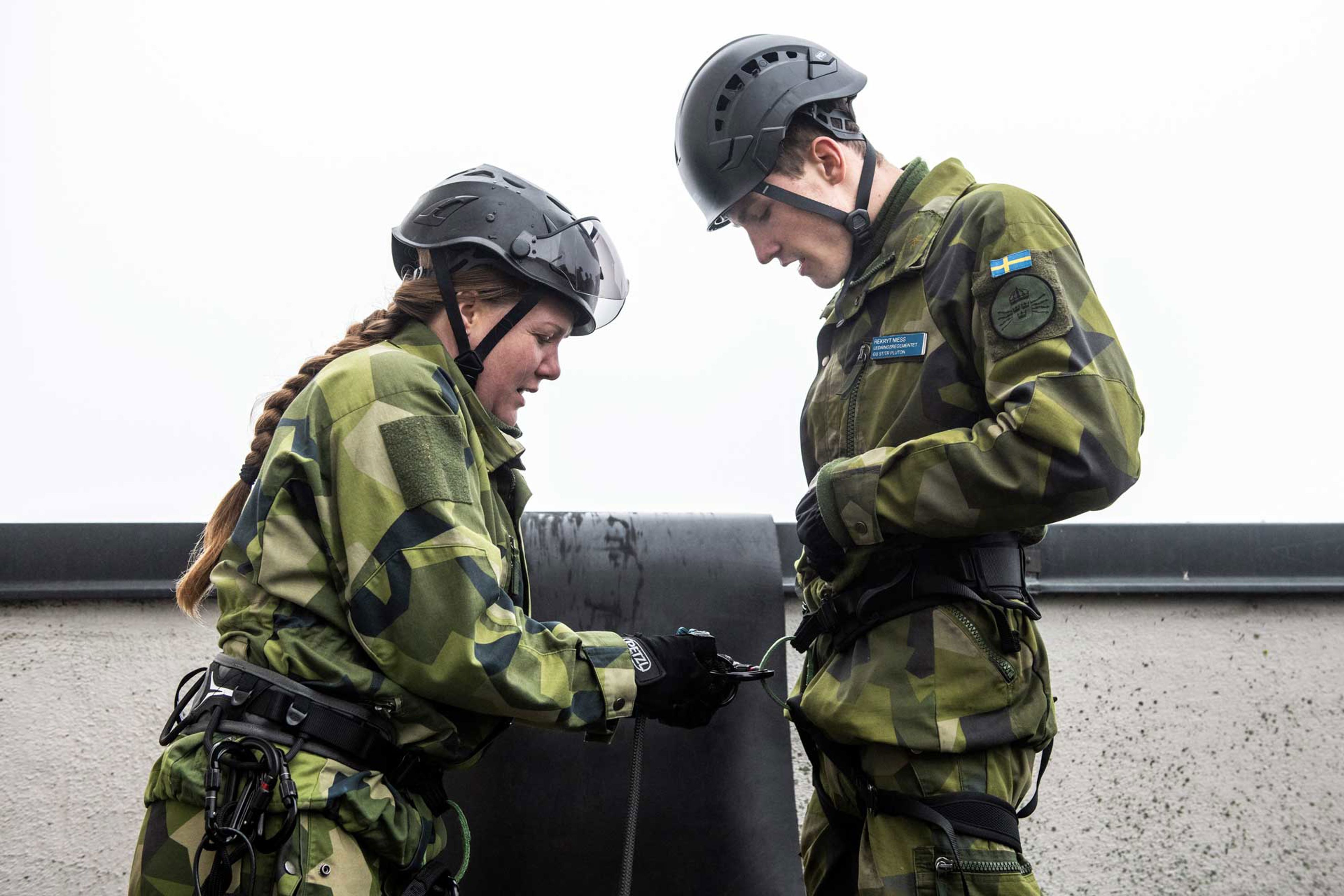 Två soldater som hjälper varandra med repelleringsutrustning.