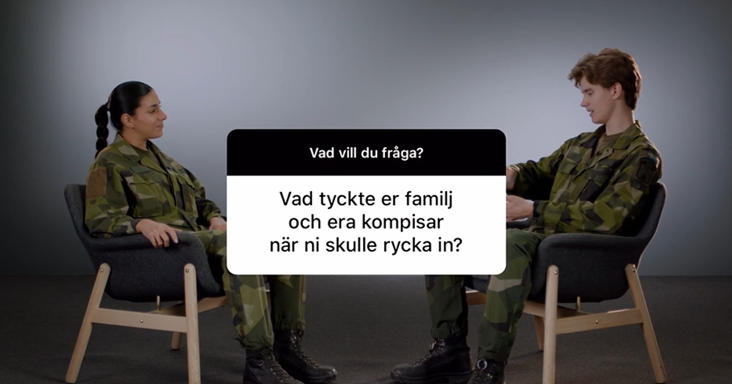 Två personer i uniform sitter mitt emot varandra i en studio och intervjuar varandra.