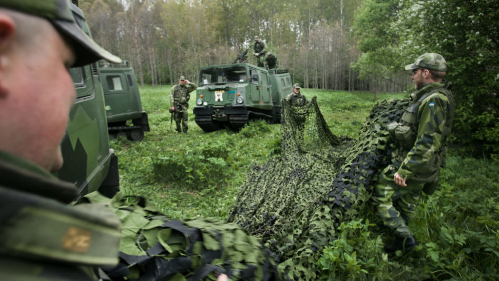 Hemvärnssoldater sätter upp kamouflagenät för att täcka sina bandvagnar