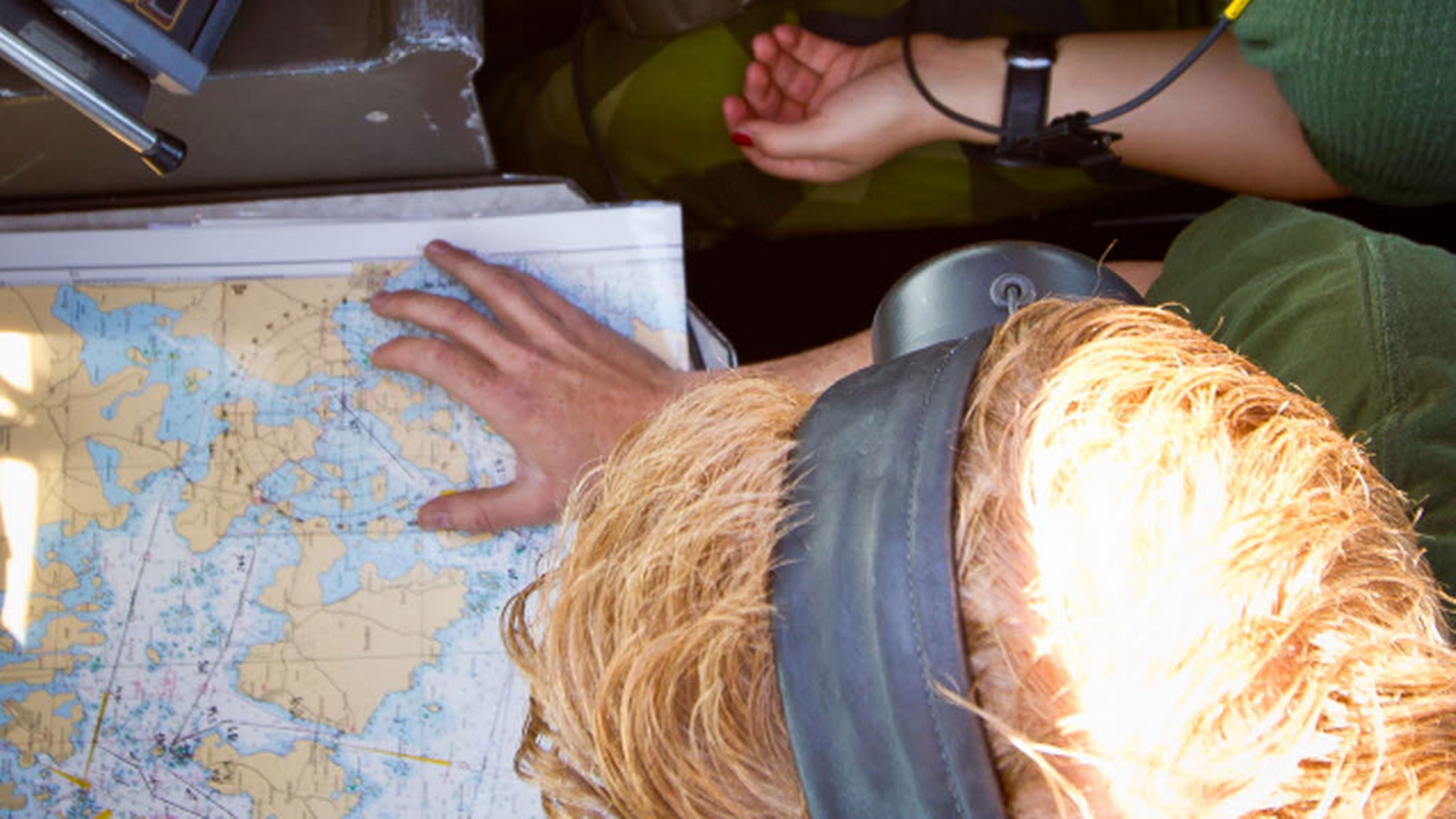 En soldat tittar ned på en karta med hörlurar på sig.