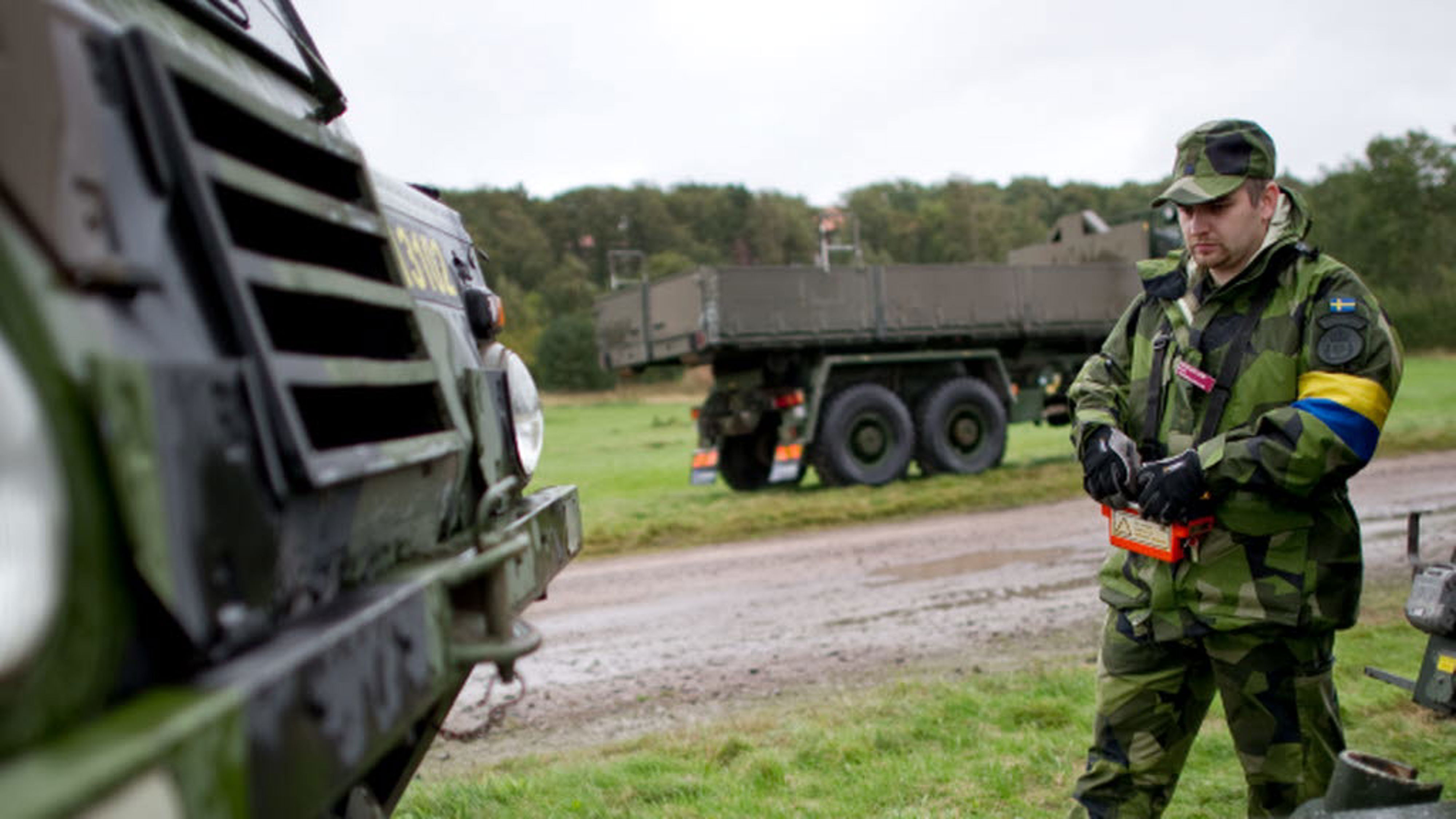 En militär står vid ett militärt fordon.