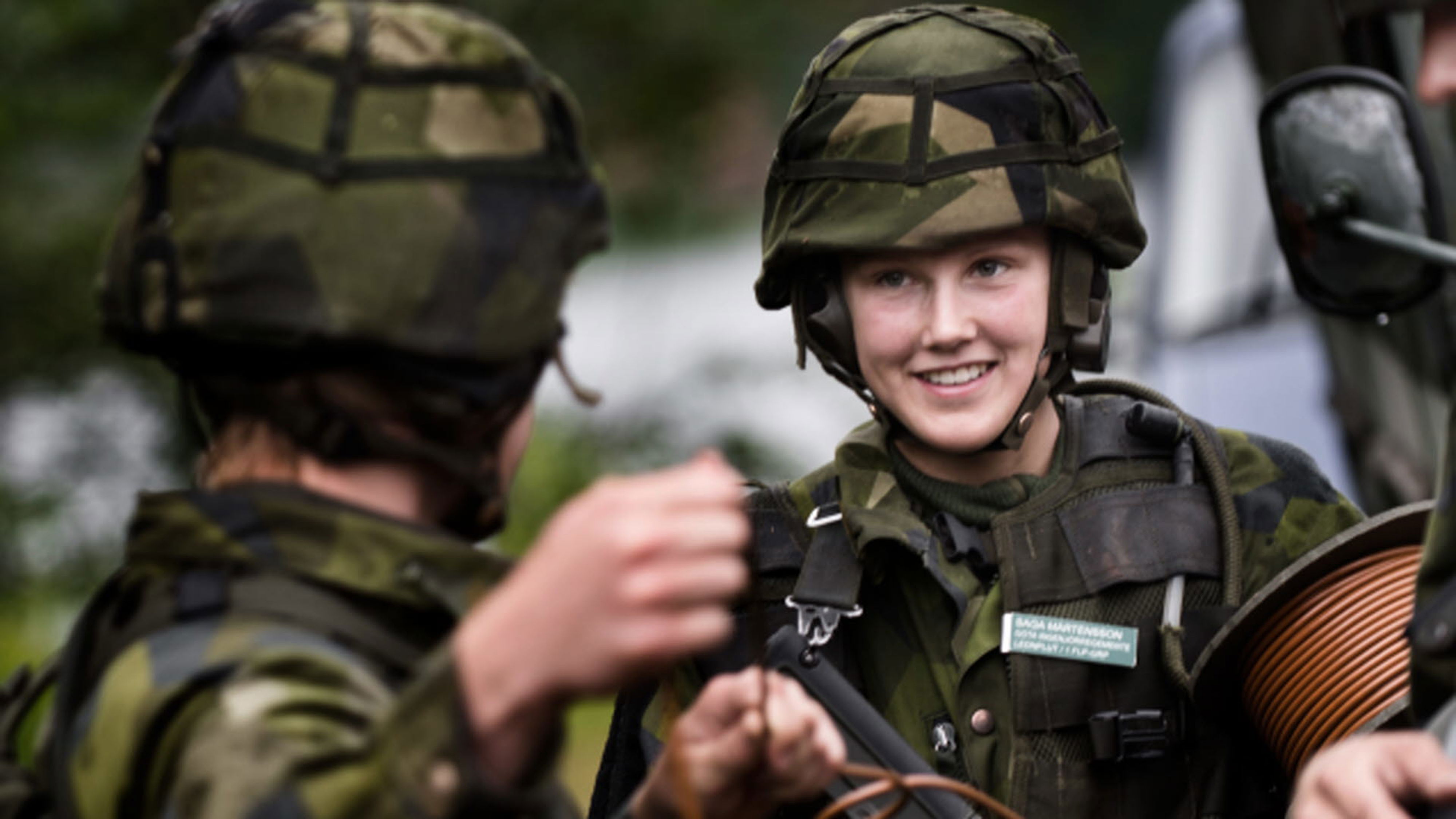 Två militärer med hjälm på tittar på varandra.