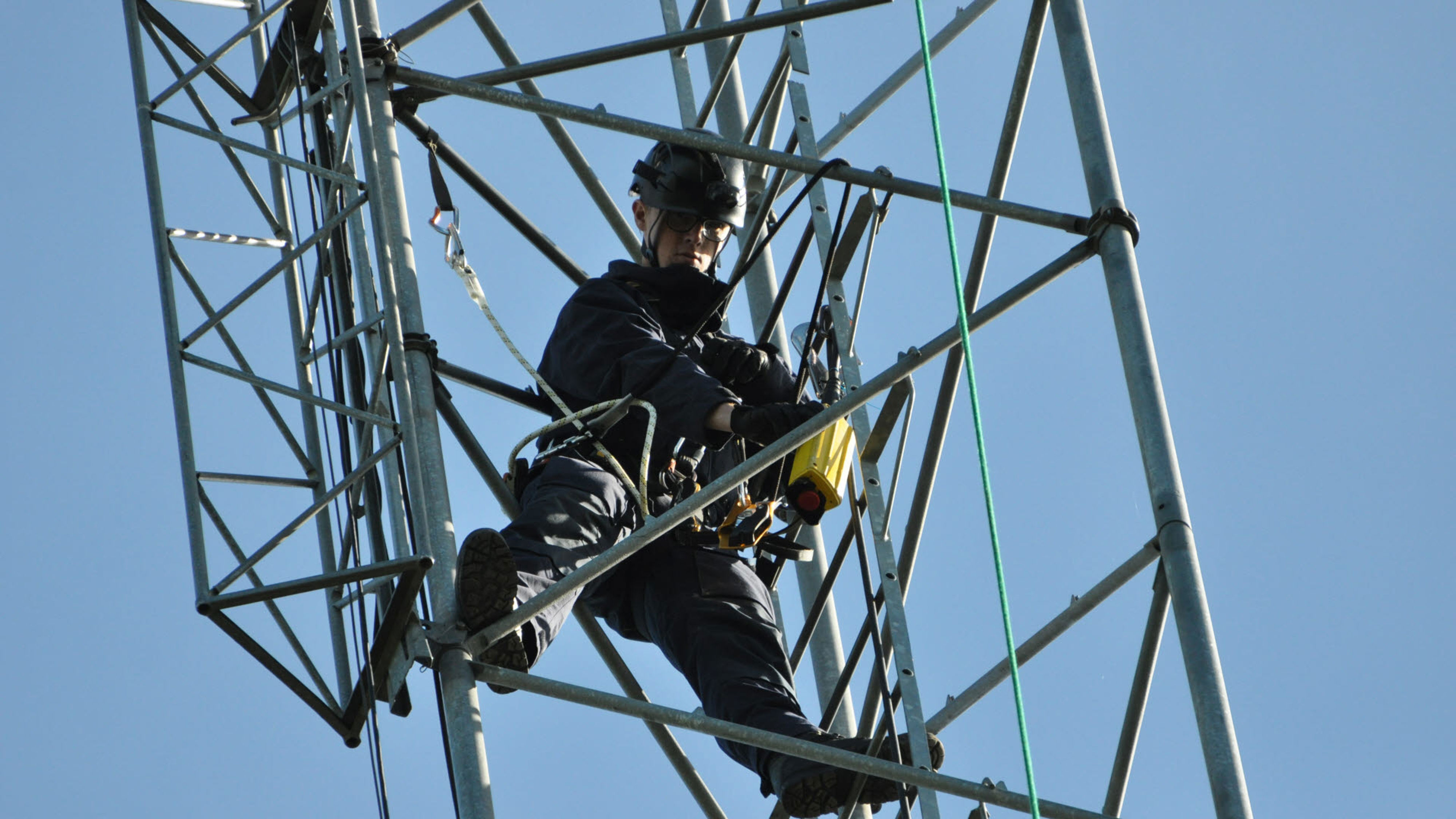 En person sitter och jobbar i en mast.
