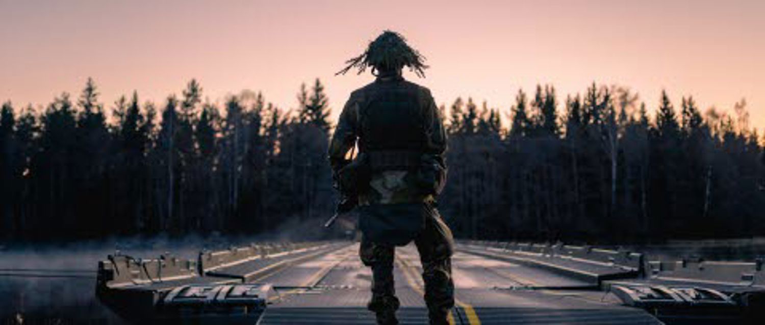 En silhuett av en soldat i solnedgången vid en skog.