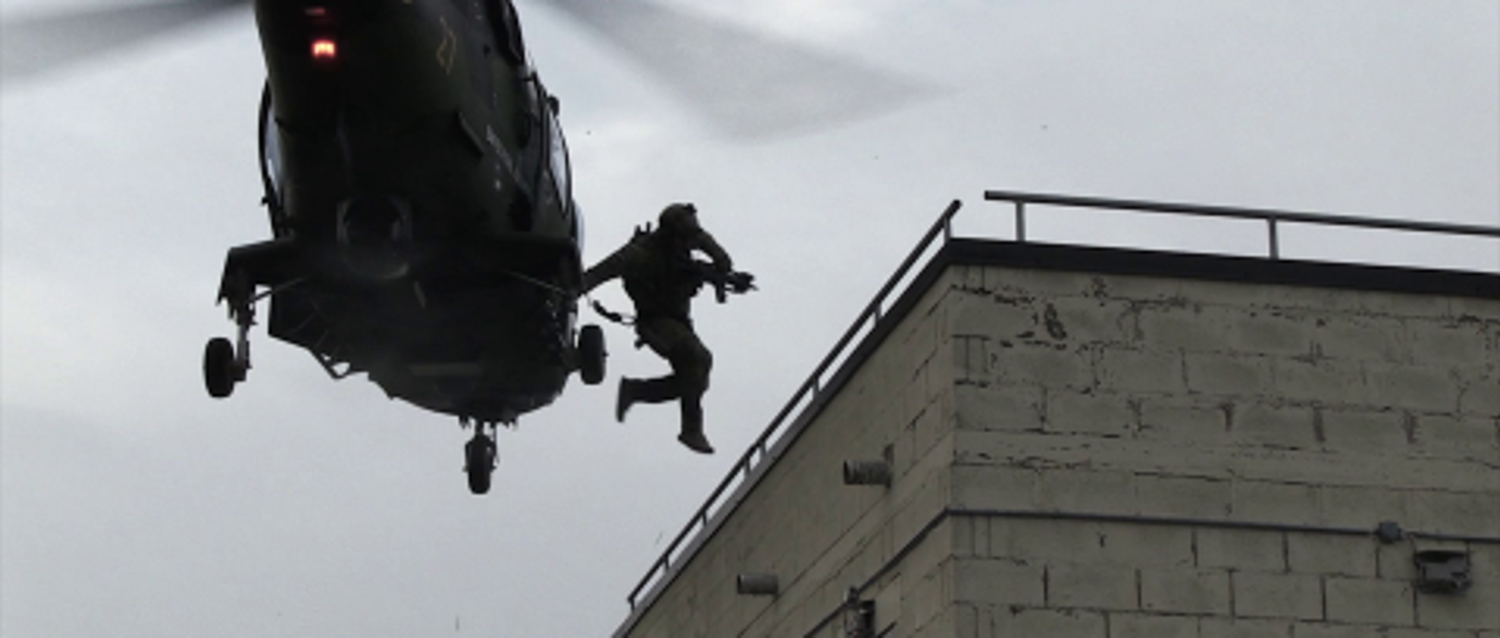 En person hoppar från en helikopter till ett hustak.