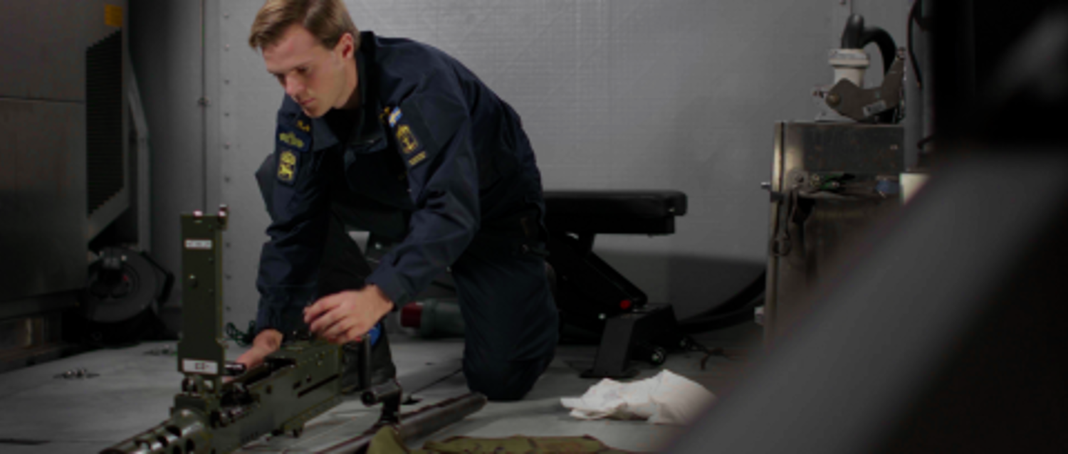 En militär lutar sig över ett större vapen.