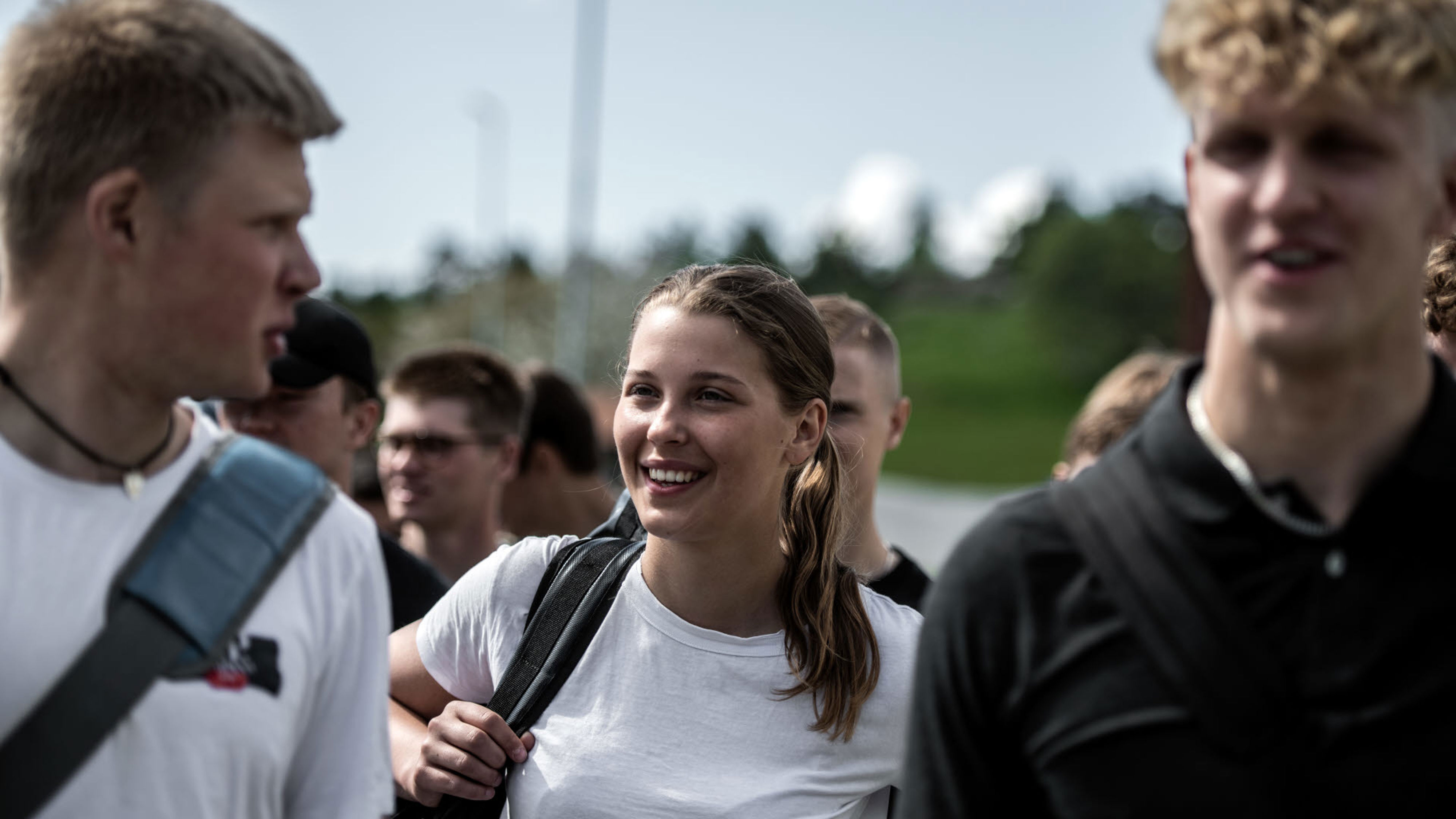 Tre personer i t-shirt tittar på varandra och ler.